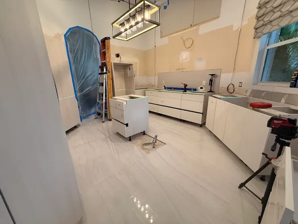 Laser-leveled cabinet install in progress on the modern kitchen.
