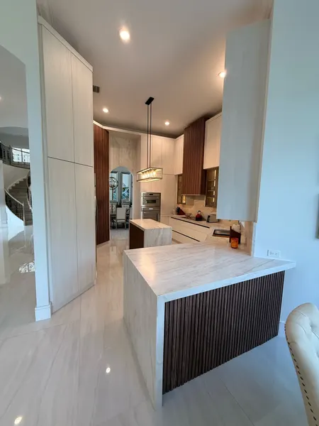 Modern woodgrain slab cabinetry with walnut slat panels on the waterfall peninsula.