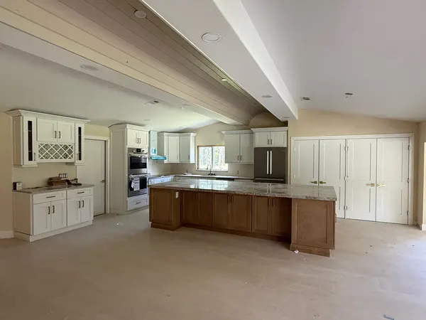 White shaker kitchen with a large stained-wood island and matching pantry doors.