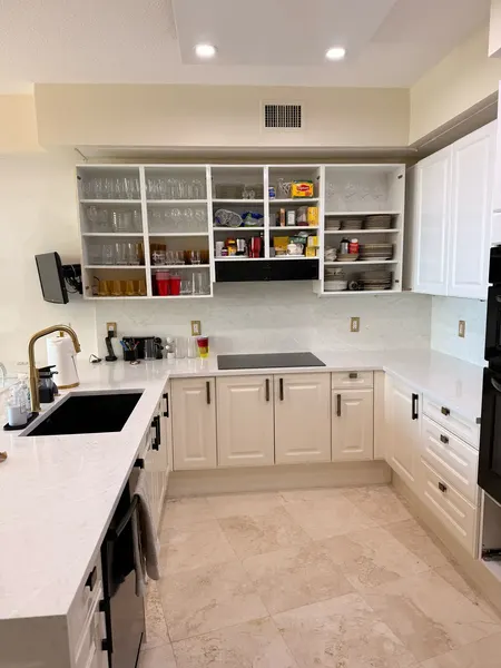 Same kitchen mid-project: upper doors off, original hardware still on the lowers.