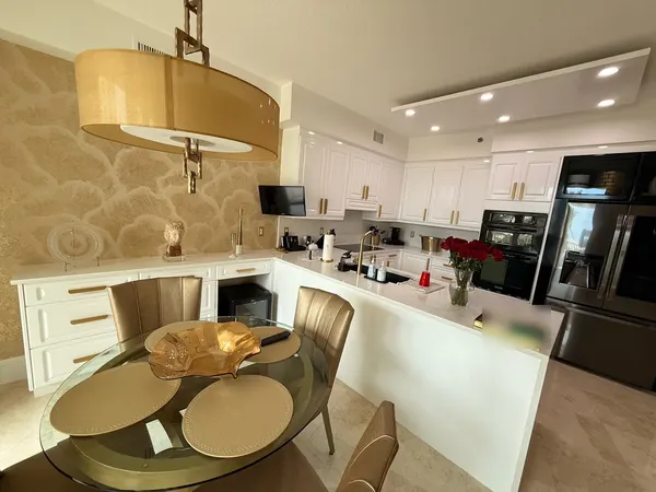 White raised-panel kitchen cabinets with brushed-gold pulls and waterfall peninsula.