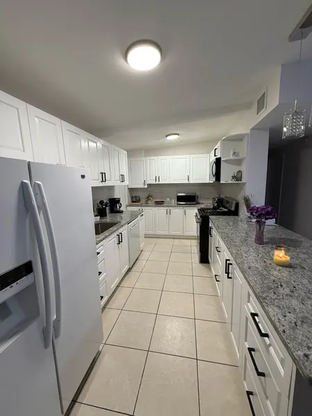 White shaker galley kitchen with matte black pulls and granite countertops.