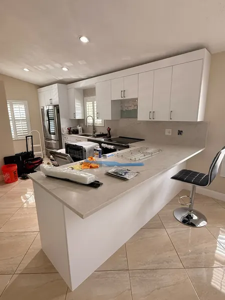 White slab-door kitchen with a breakfast-bar peninsula, just installed.