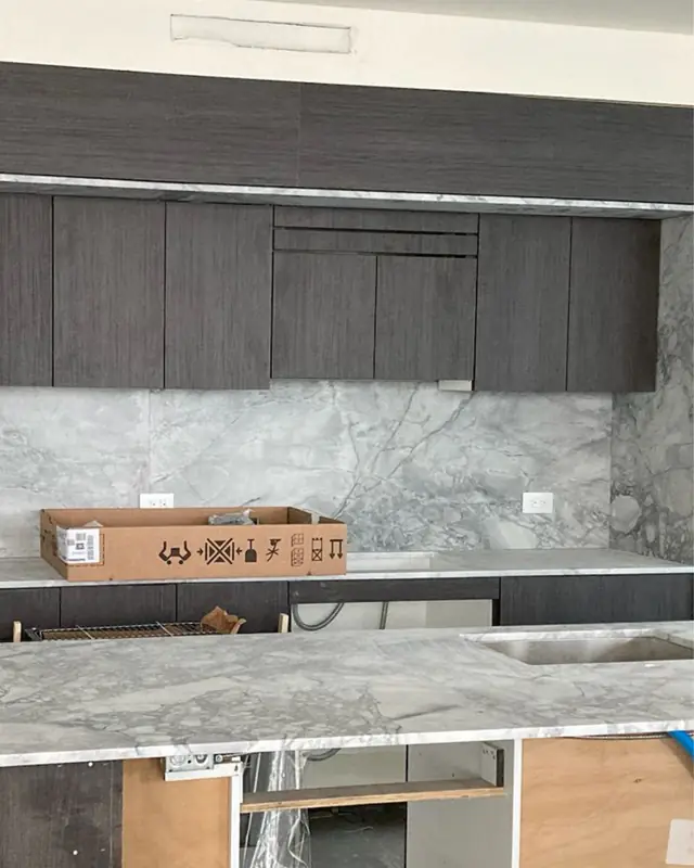 Dark kitchen cabinets with a marble top during installation