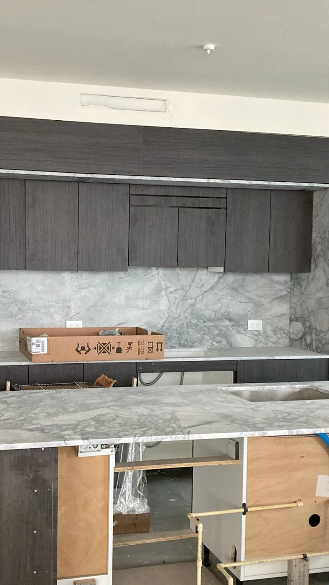 Dark kitchen cabinets with marble countertop during installation