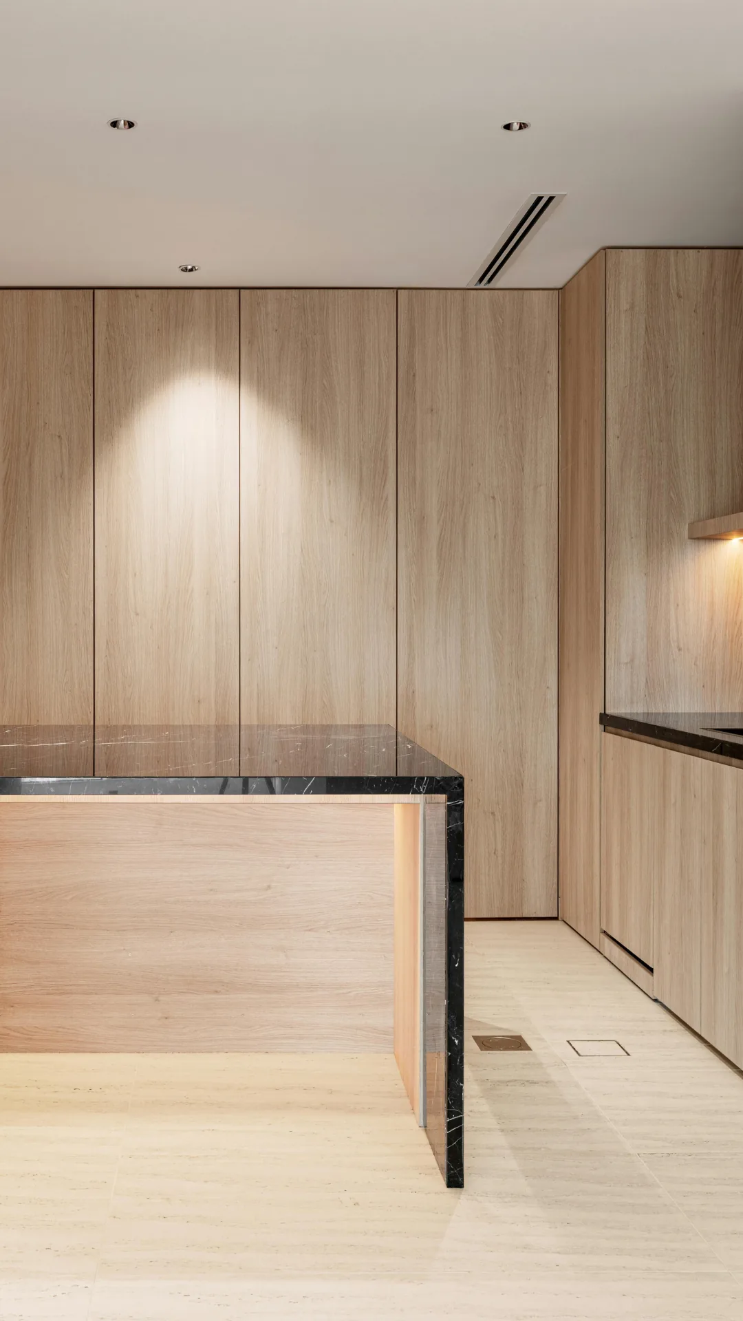 Light wood kitchen with floor-to-ceiling cabinets and a stone island