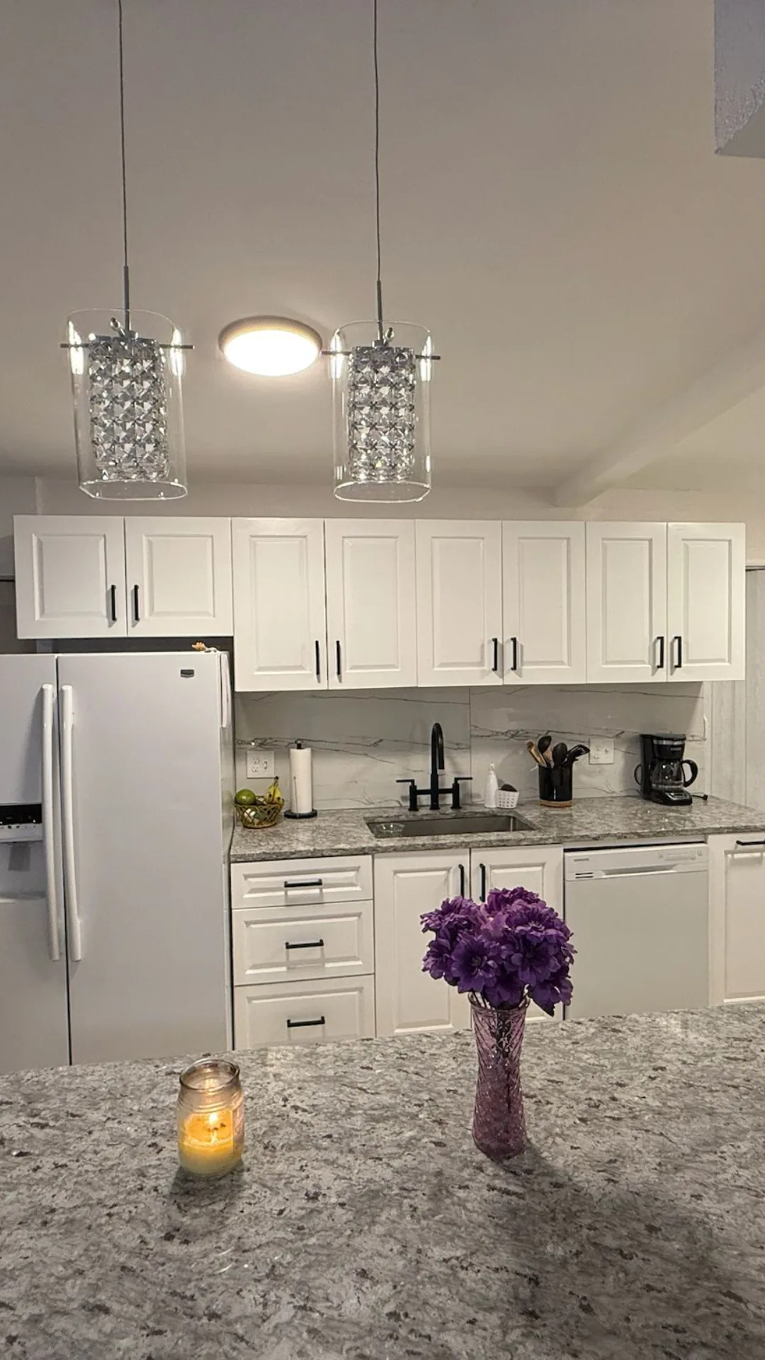 White kitchen with pendant lights and granite island