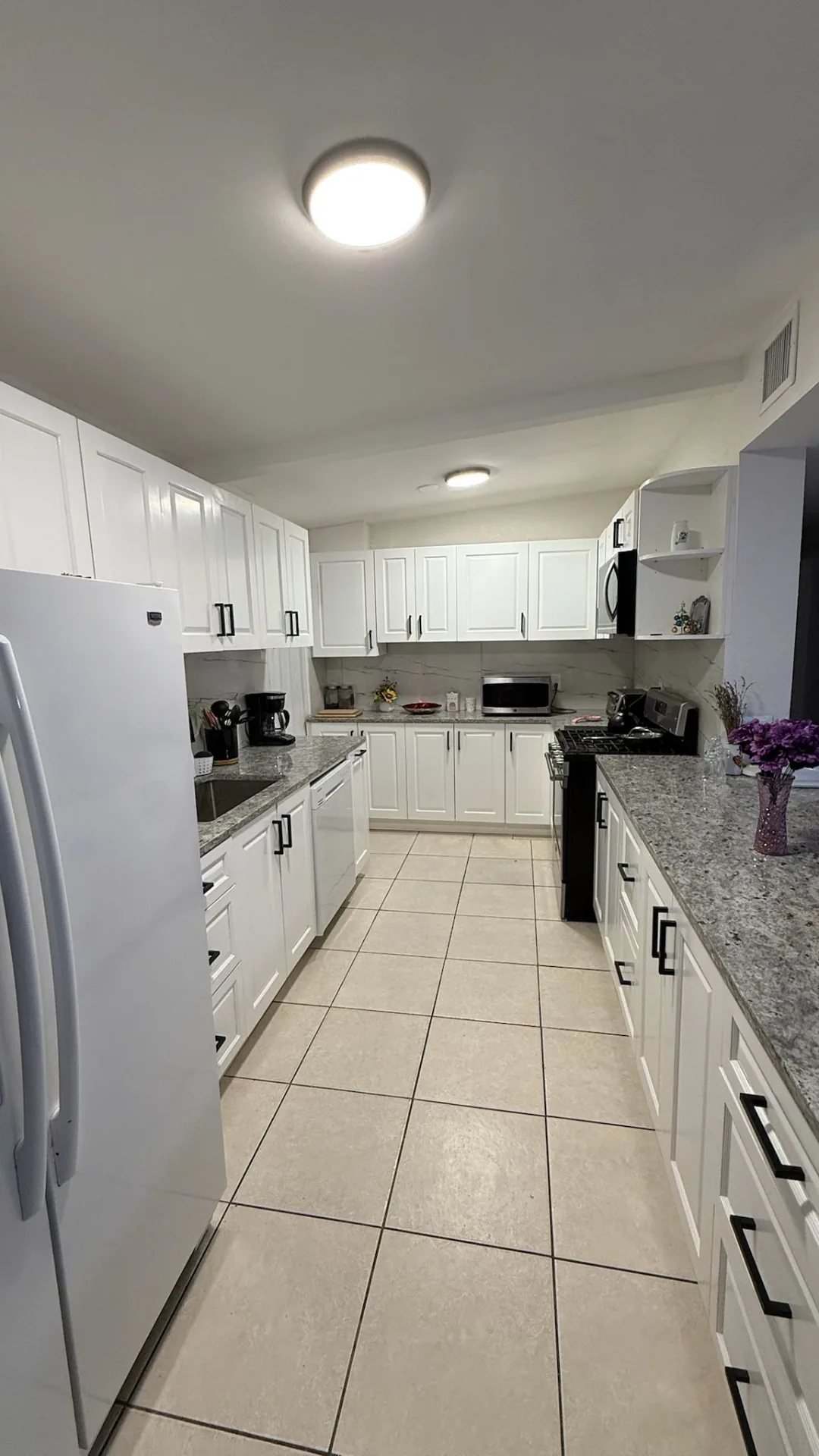 White kitchen cabinets with granite countertops and tile floor