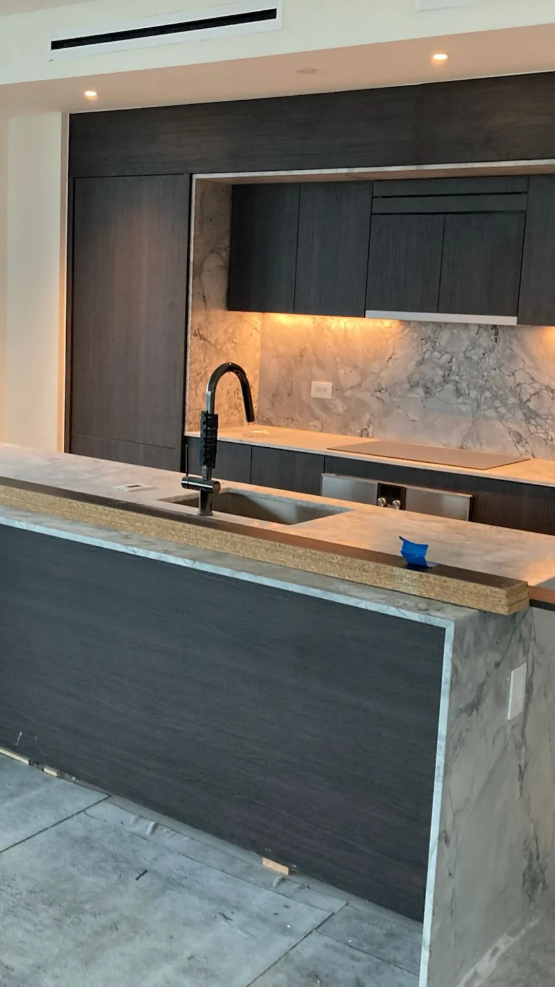 Dark kitchen cabinets with marble backsplash and LED lighting
