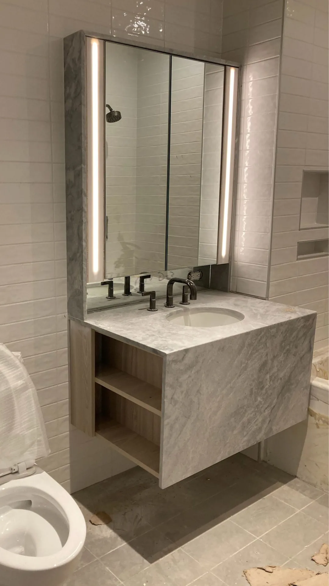 Floating bathroom vanity with stone top and lighted mirror